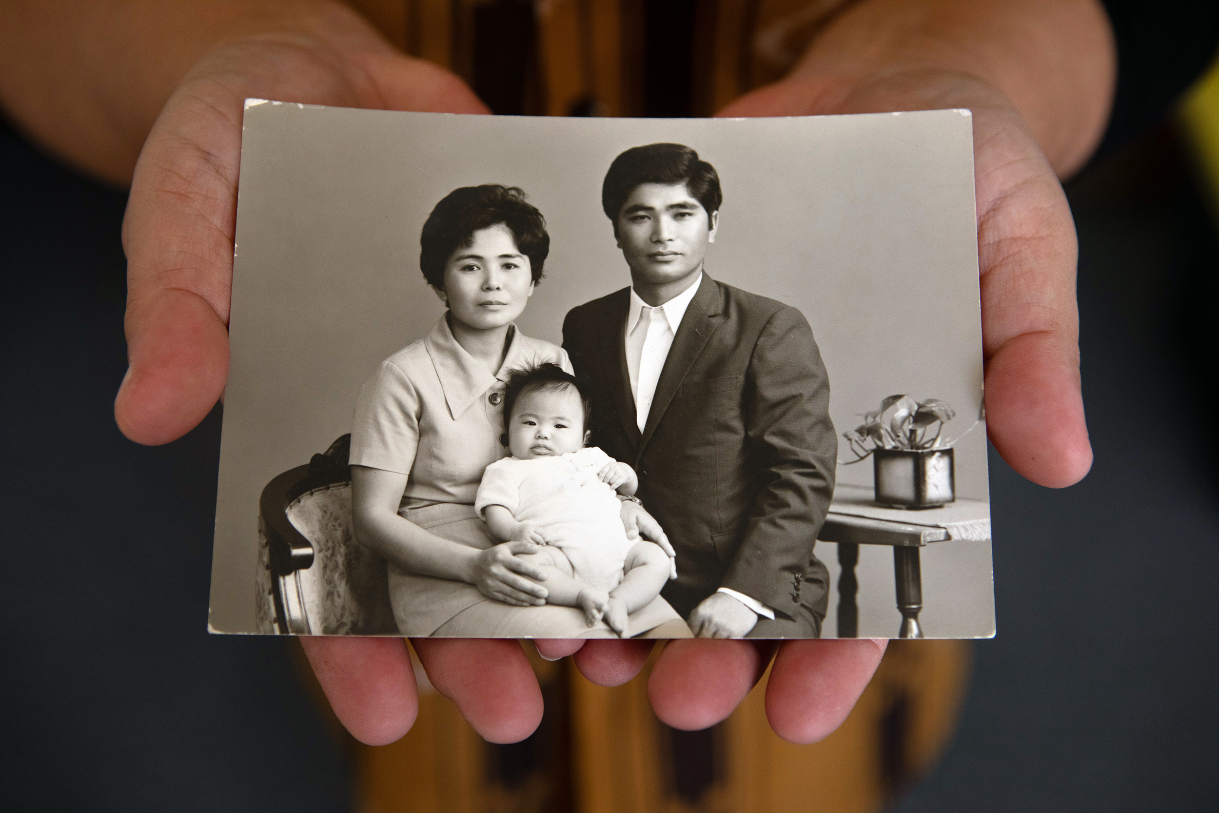 Woman holding black and white photo of her parents holding her as a baby.
