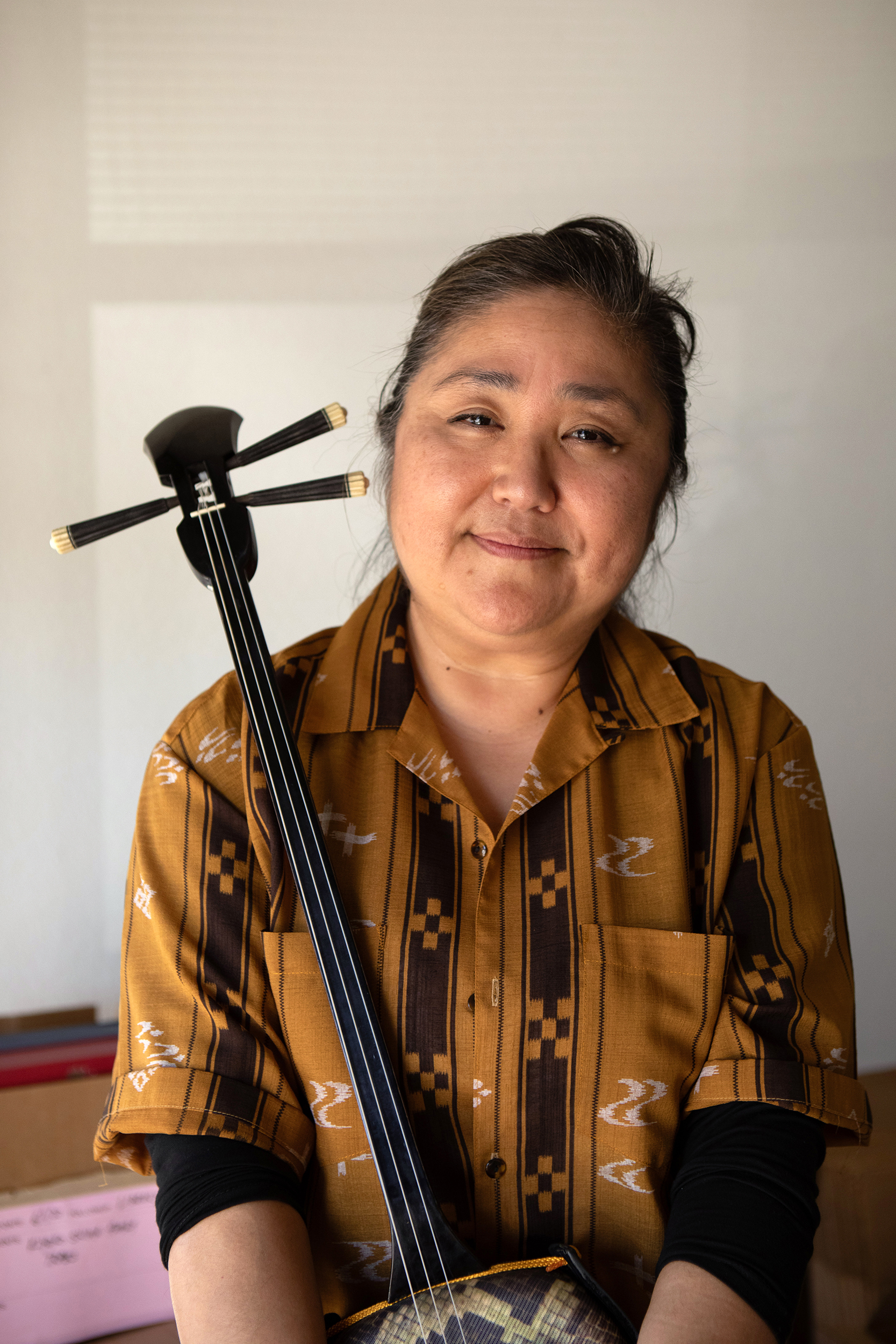 Woman posing holding the sanshin, an Okinawan instrument.